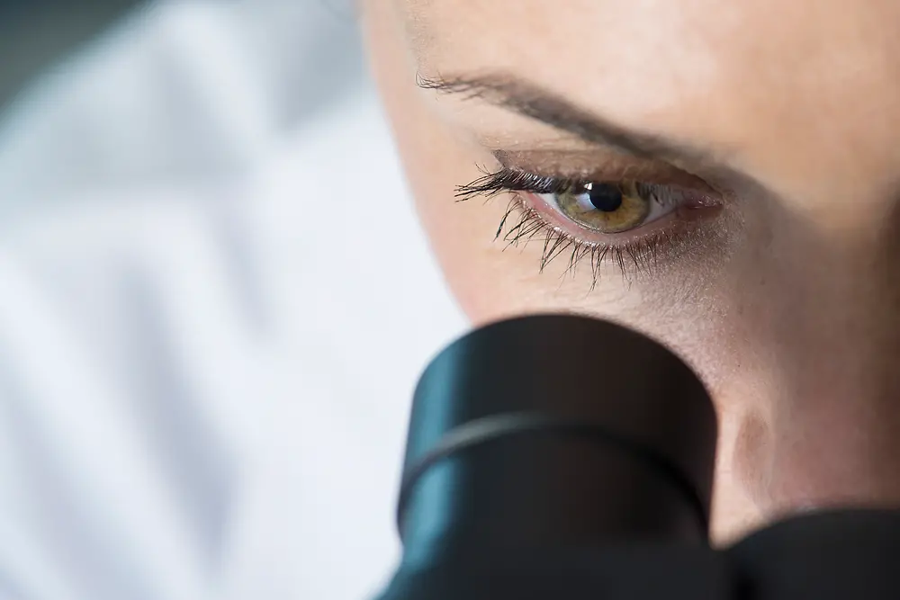 Oko ženske, ki gleda v mikroskop