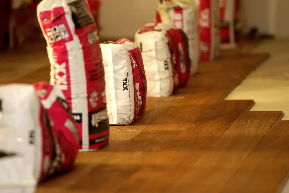 Um den Klebeprozess zu unterstützen, wurden die Massivdielen mit aufgestellten Spachtelmasse-Säcken beschwert